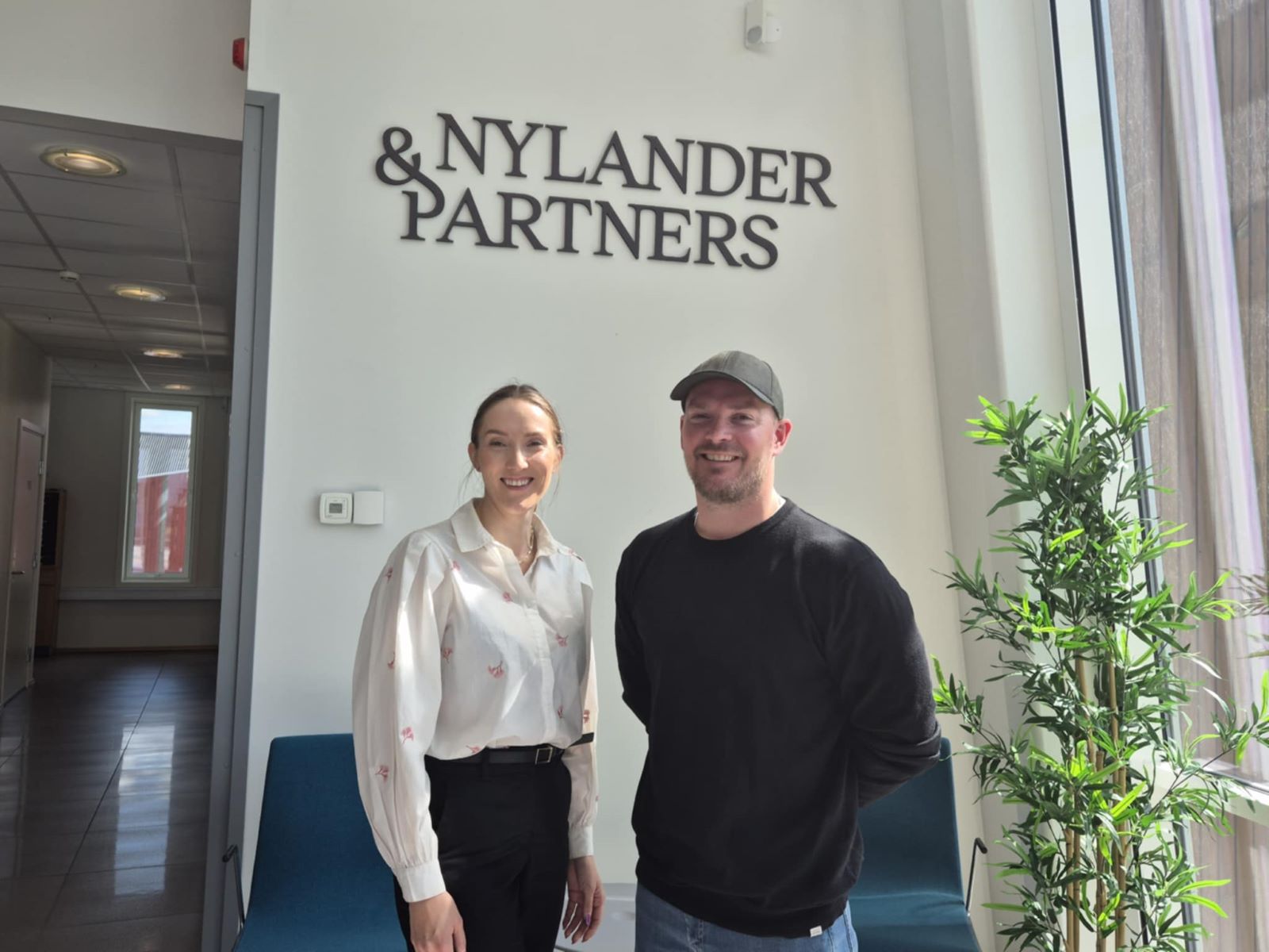 Silje og Aleksander foran Nylander &Partners logo
