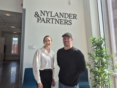 Silje og Aleksander foran Nylander &Partners logo